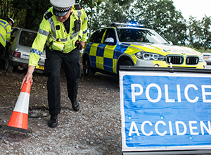 A police officer placing a red cone on a hard core road side